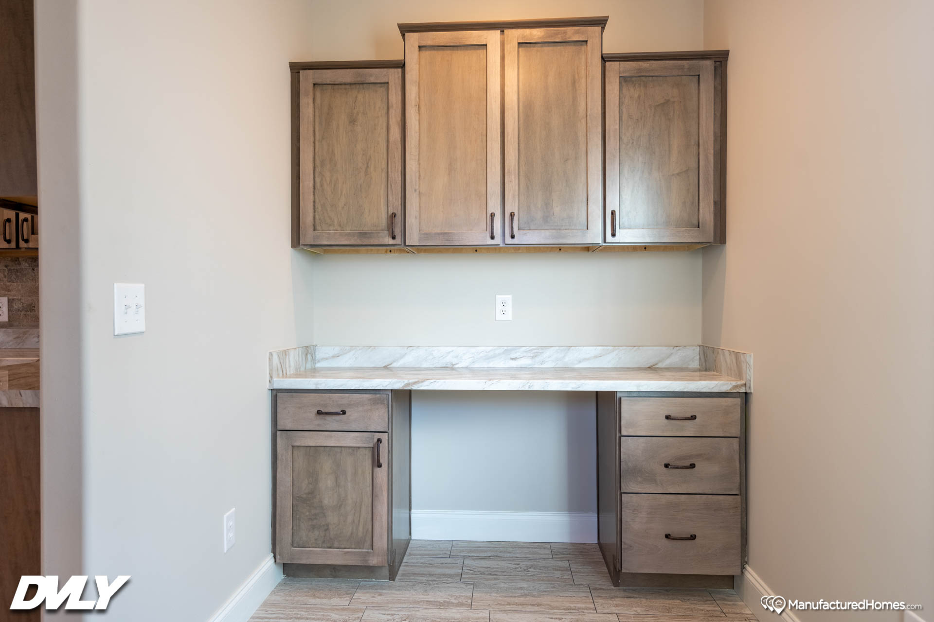 Built-in office nook with light wood cabinets and drawers, marble countertop, and neutral walls, creating a clean, organized, and modern workspace.