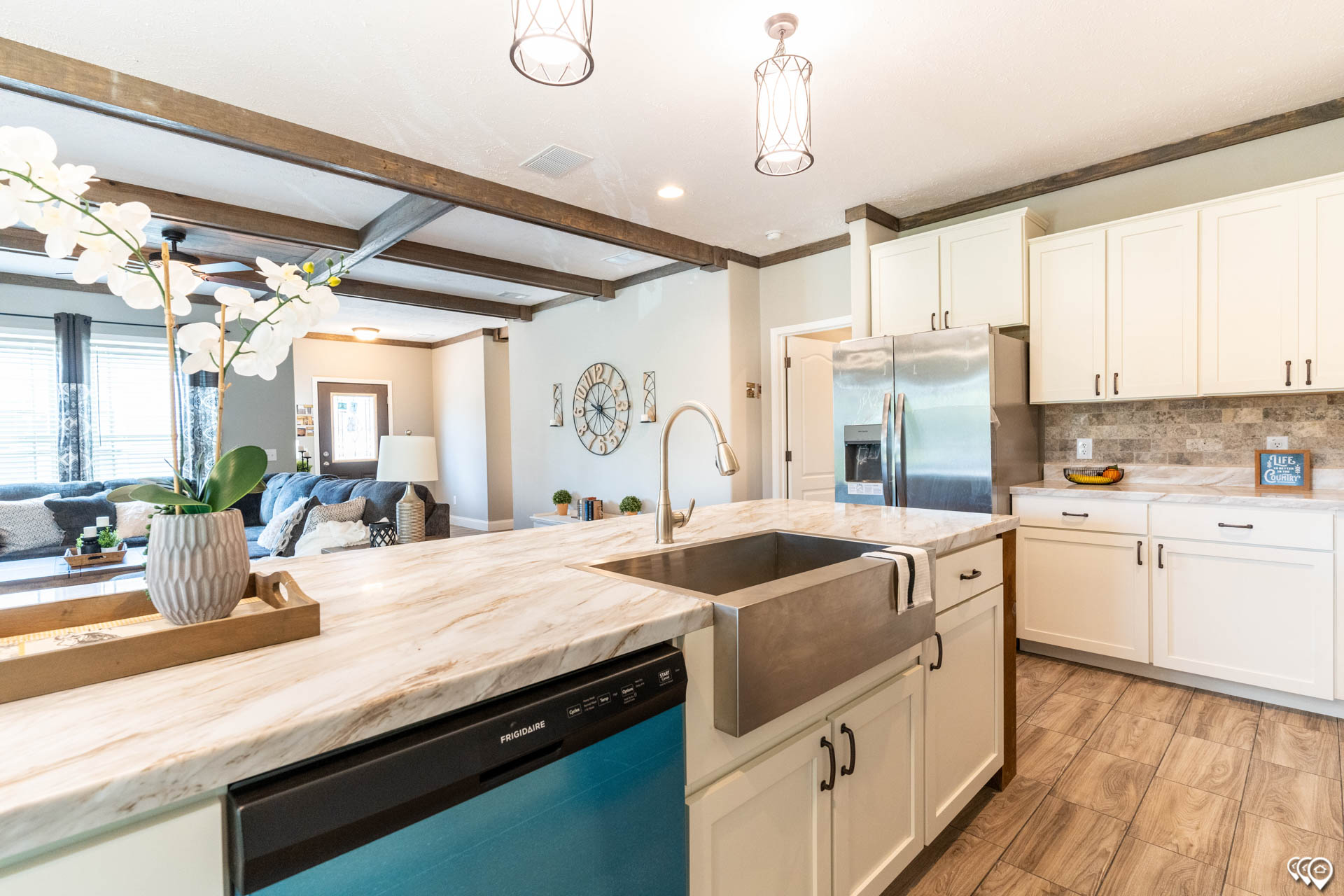 Modern kitchen with marble countertops, farmhouse sink, and stainless steel appliances. White cabinets contrast with warm, wooden flooring. Relaxing ambiance.