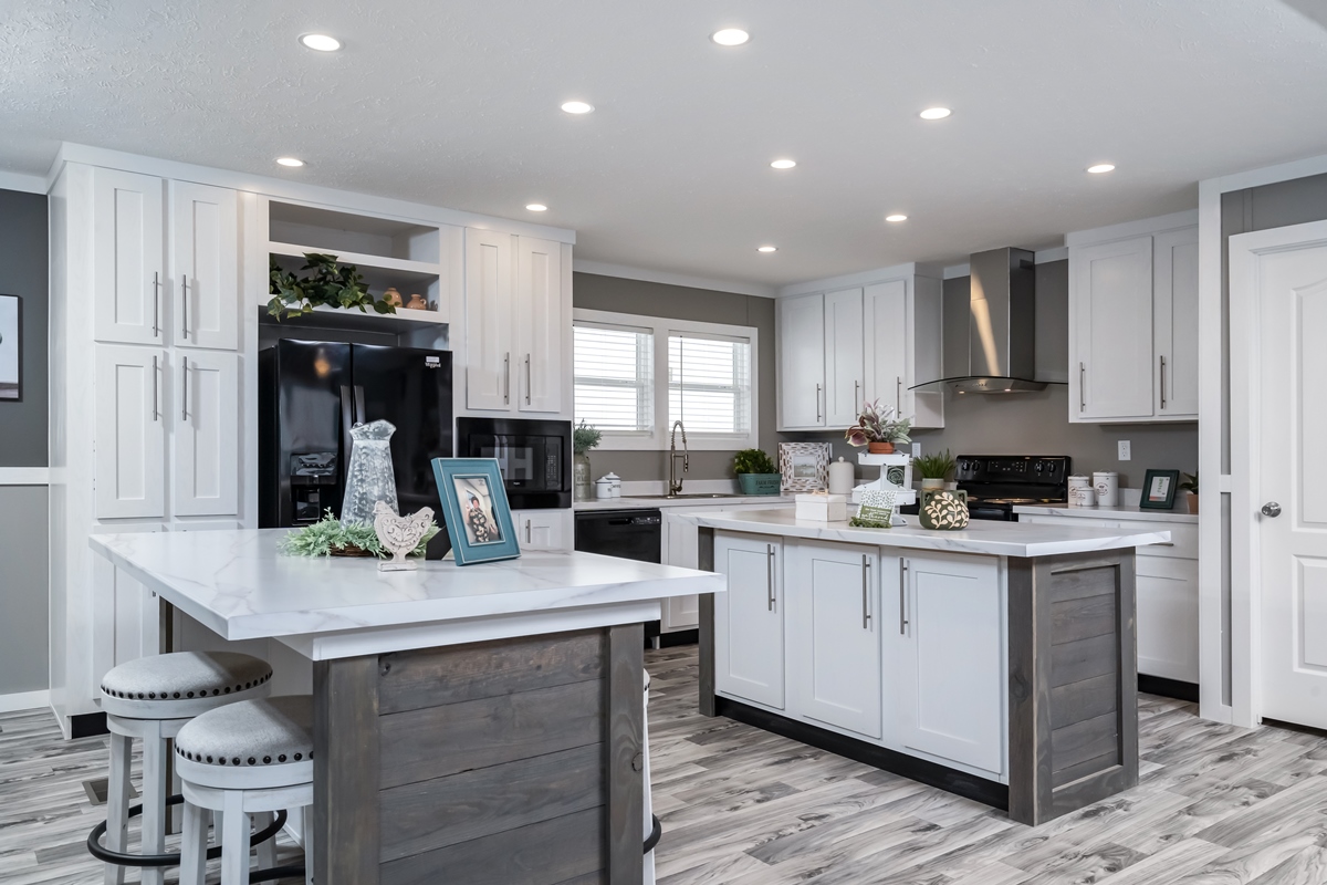 Modern kitchen with white cabinets and dark wood accents. Features a large island, black appliances, recessed lighting, and decorative items, creating an inviting, elegant ambiance.