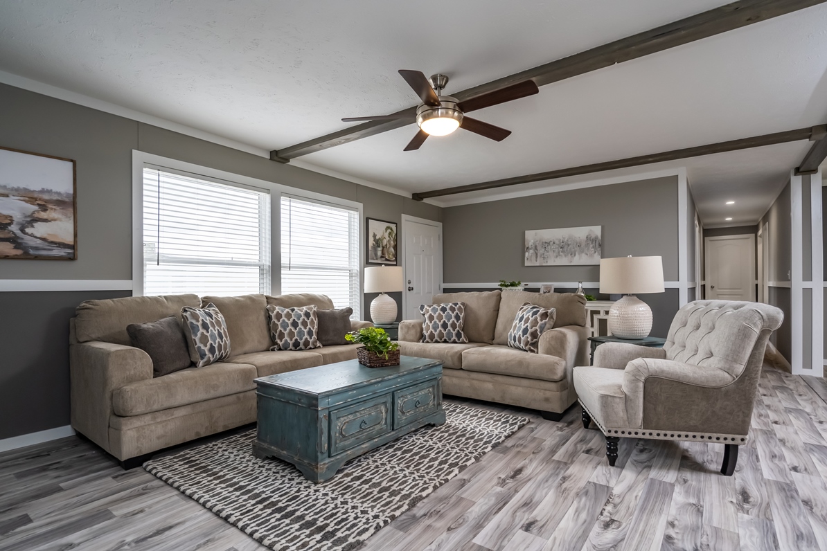Stylish living room with gray walls, beige sofas, an armchair, patterned pillows, and a blue coffee table on a geometric rug. Elegant and cozy.
