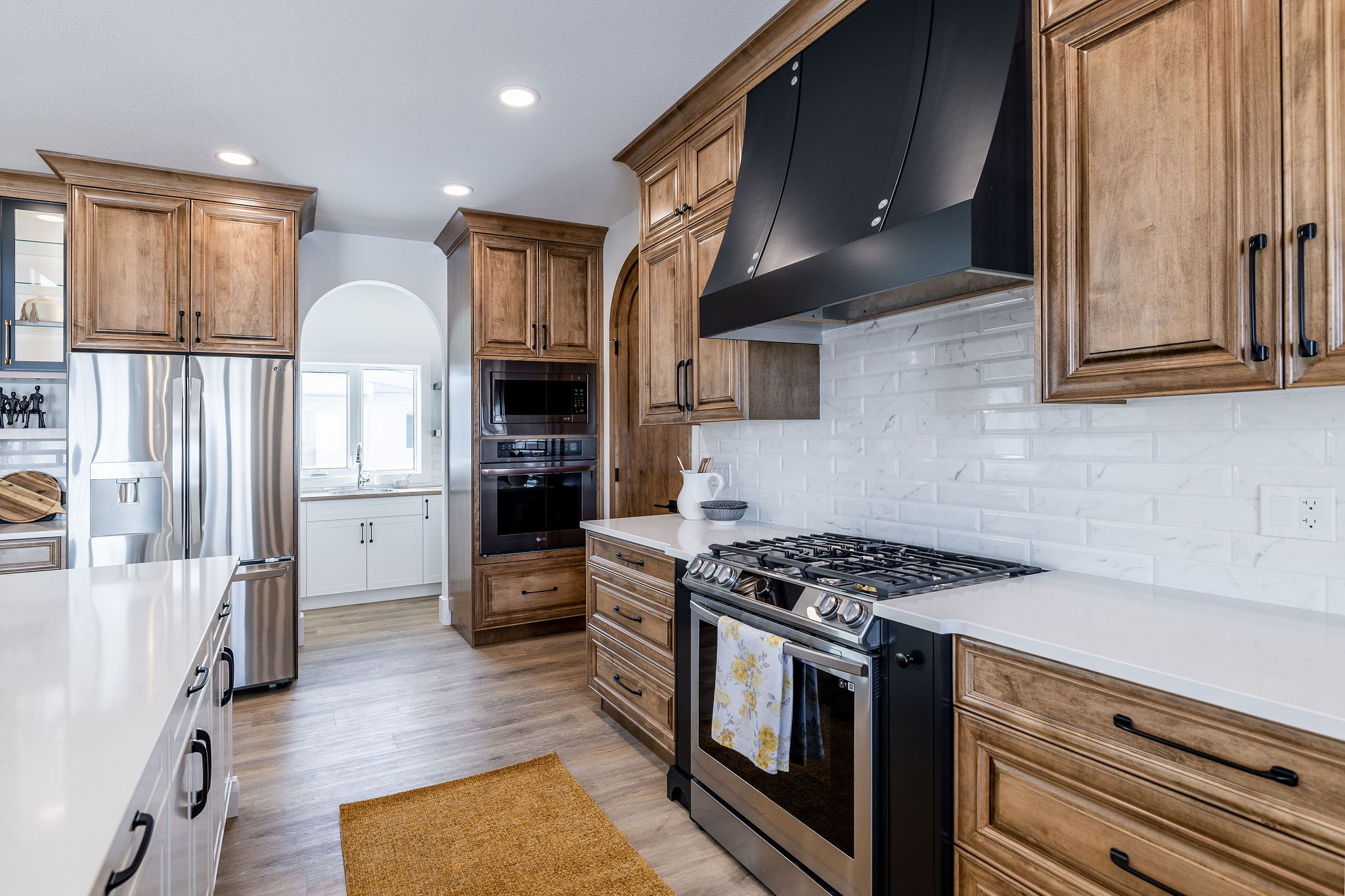 Spacious kitchen with wooden cabinets, stainless steel appliances, and a central gas stove. Bright lighting creates a warm, inviting atmosphere.