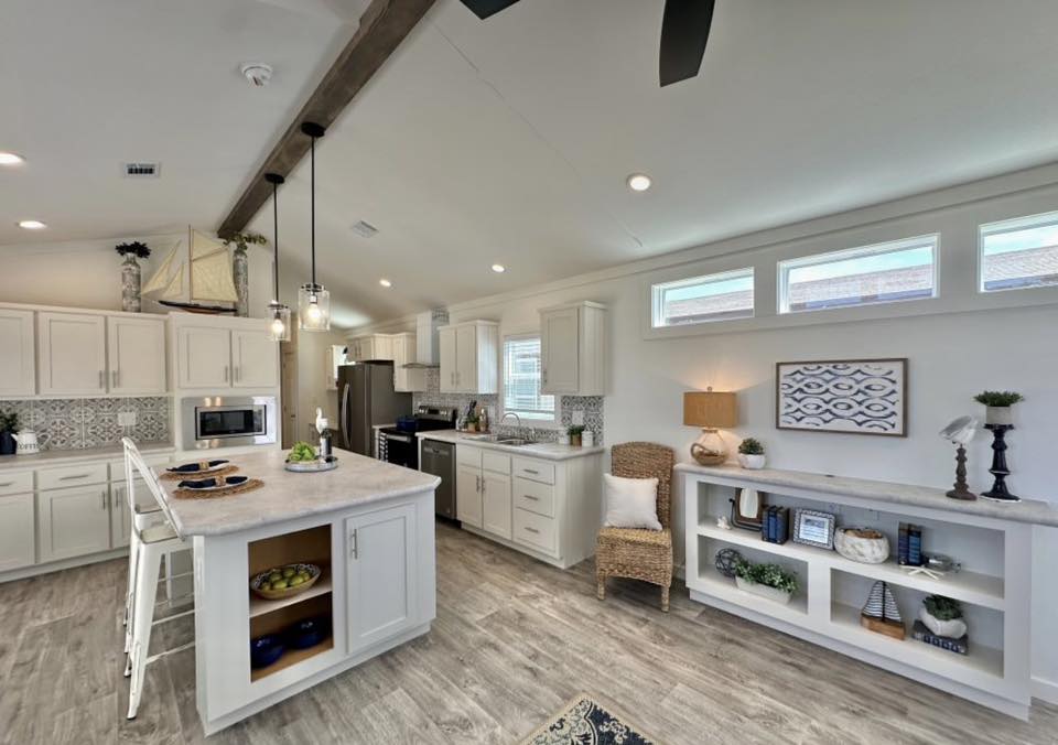 Bright, modern kitchen with white cabinets, marble countertops, and patterned tile backsplash. Warm wood tones and decor create a welcoming atmosphere.