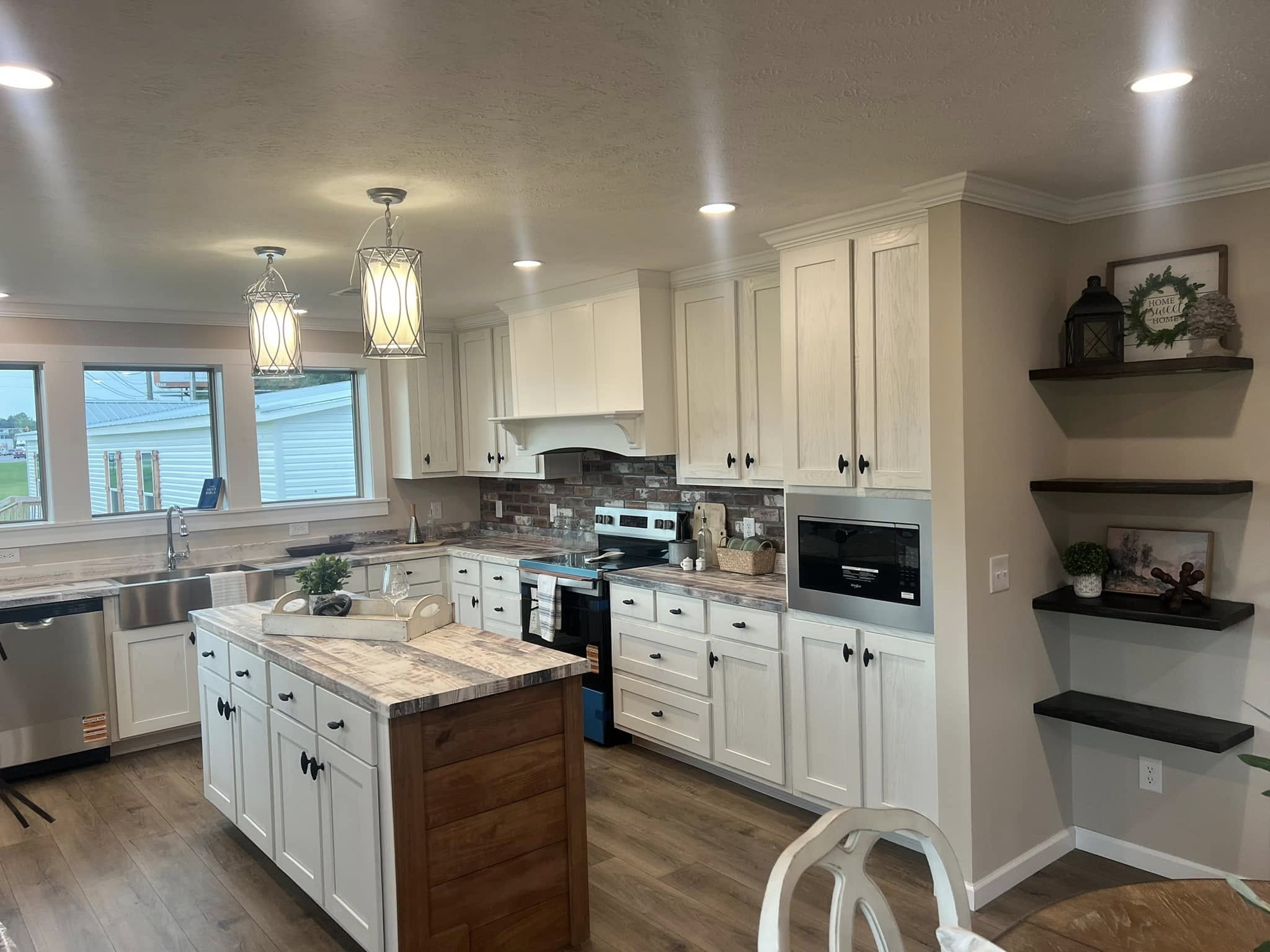 Spacious kitchen with white cabinets, a rustic island, and stainless steel appliances. Pendant lights hang from the ceiling, creating a warm ambiance.