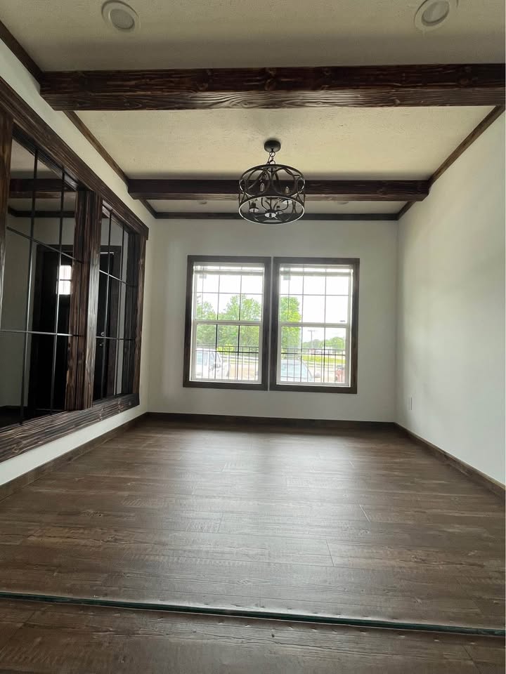 Wooden ceiling with a large black fan at the center, surrounded by four round white lights. The decor feels rustic and modern.