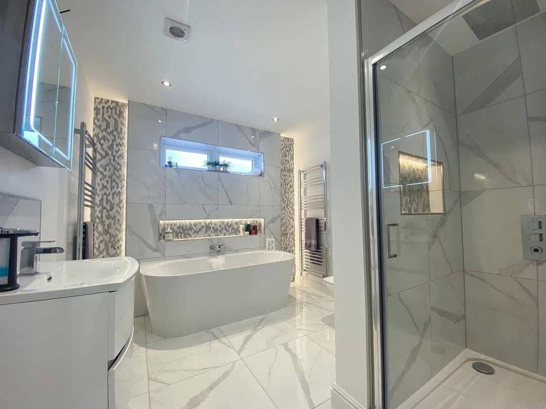 Modern bathroom with sleek design, featuring a freestanding bathtub, glass-enclosed shower, marble tiles, and a large mirror. Bright and clean ambiance.