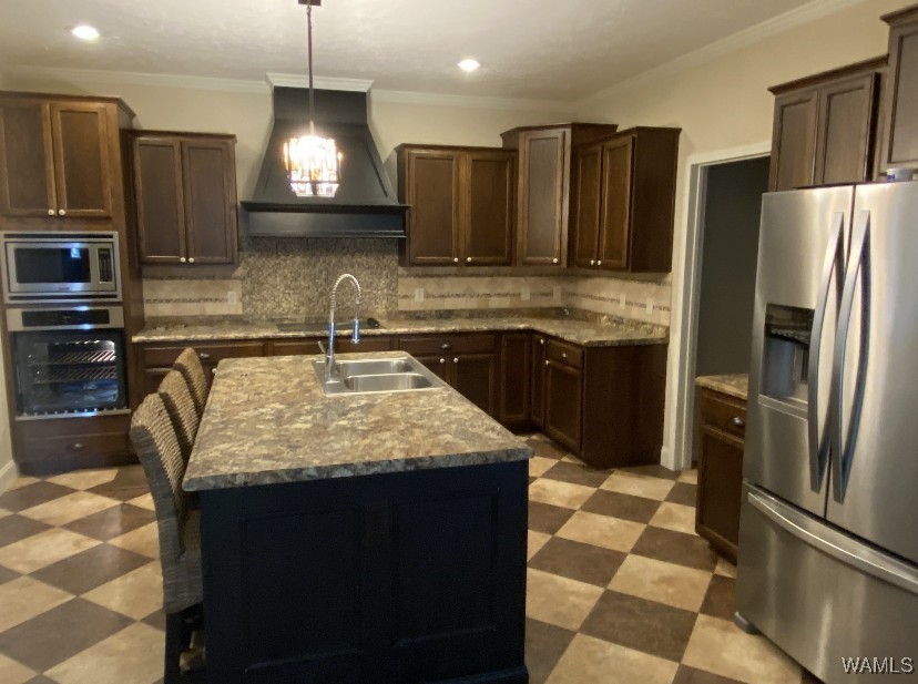 Spacious kitchen with dark wood cabinets, granite countertops, and a central island with a sink. Stainless steel appliances. Warm, inviting tone.
