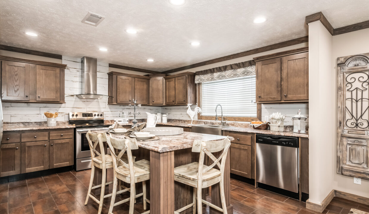 Warm, inviting kitchen with rustic wooden cabinets, a central island with four stools, stainless steel appliances, and ample natural light from a large window.