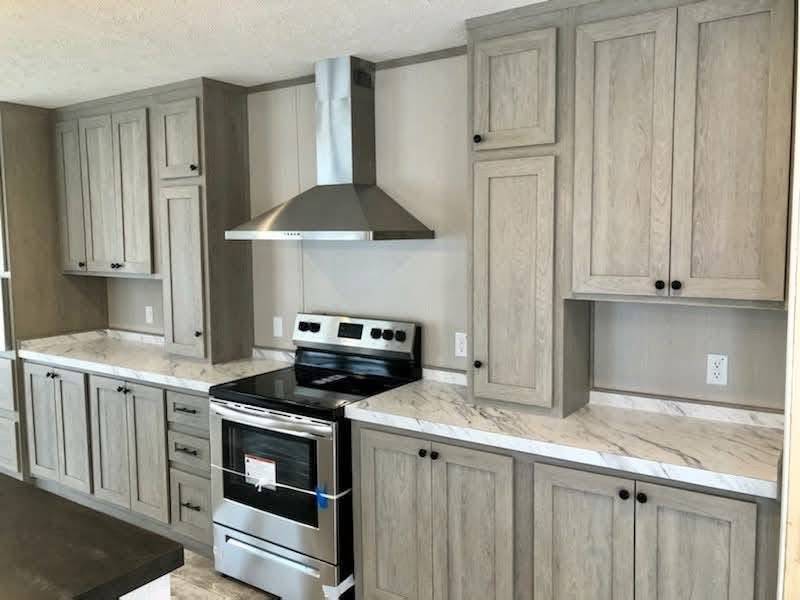 Modern kitchen with light gray cabinets, a stainless steel oven, and a range hood. Marble countertops add elegance, creating a clean, sophisticated look.