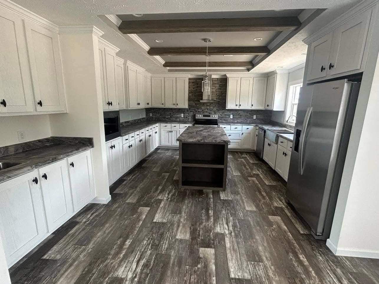 Spacious modern kitchen with white cabinets, dark countertops, stainless steel appliances, and a central island. Wooden beams add a cozy touch.