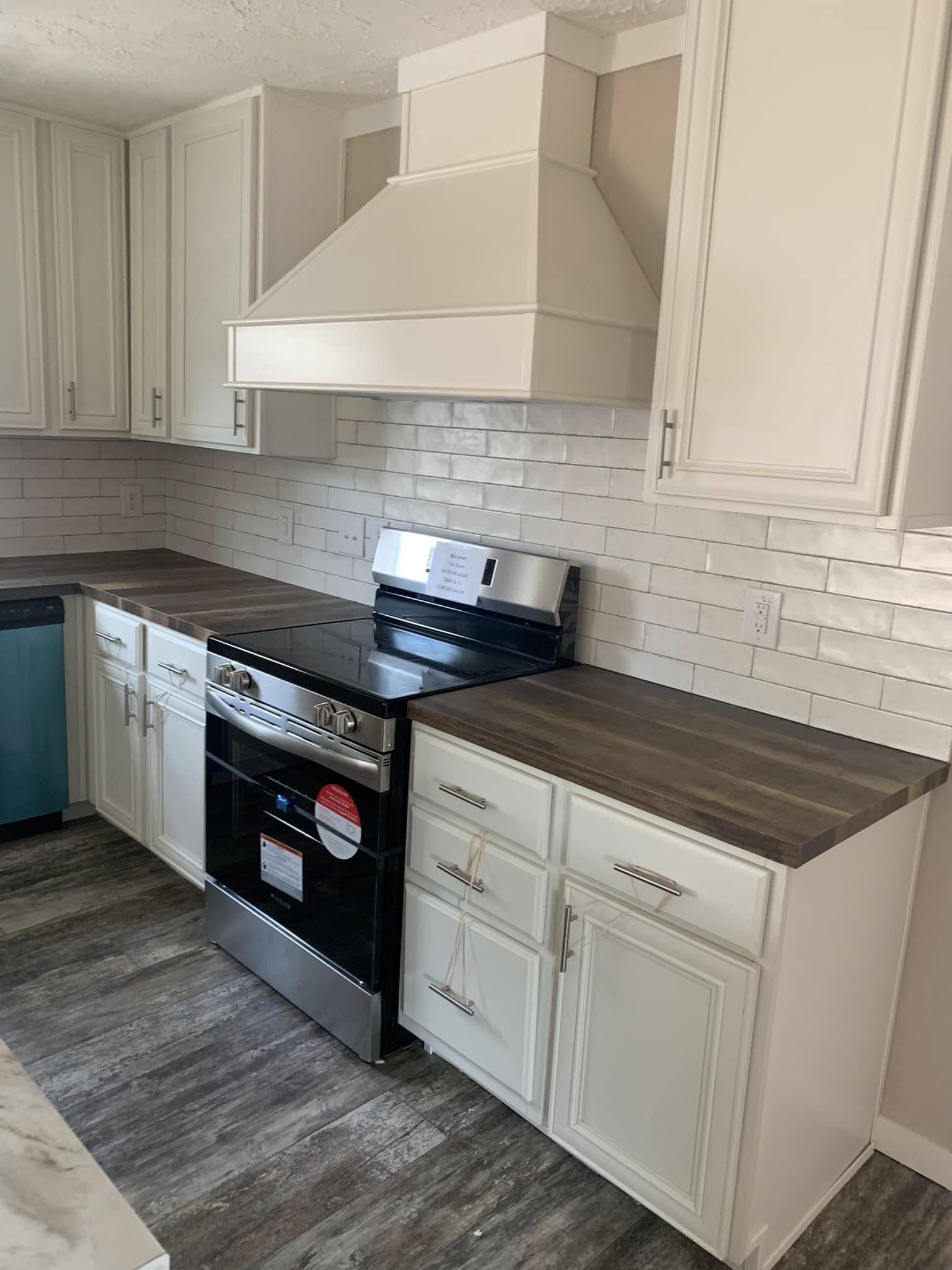 Modern kitchen with white cabinets, dark wood countertops, and a stainless steel oven. White subway tiles adorn the walls, creating a sleek and clean look.