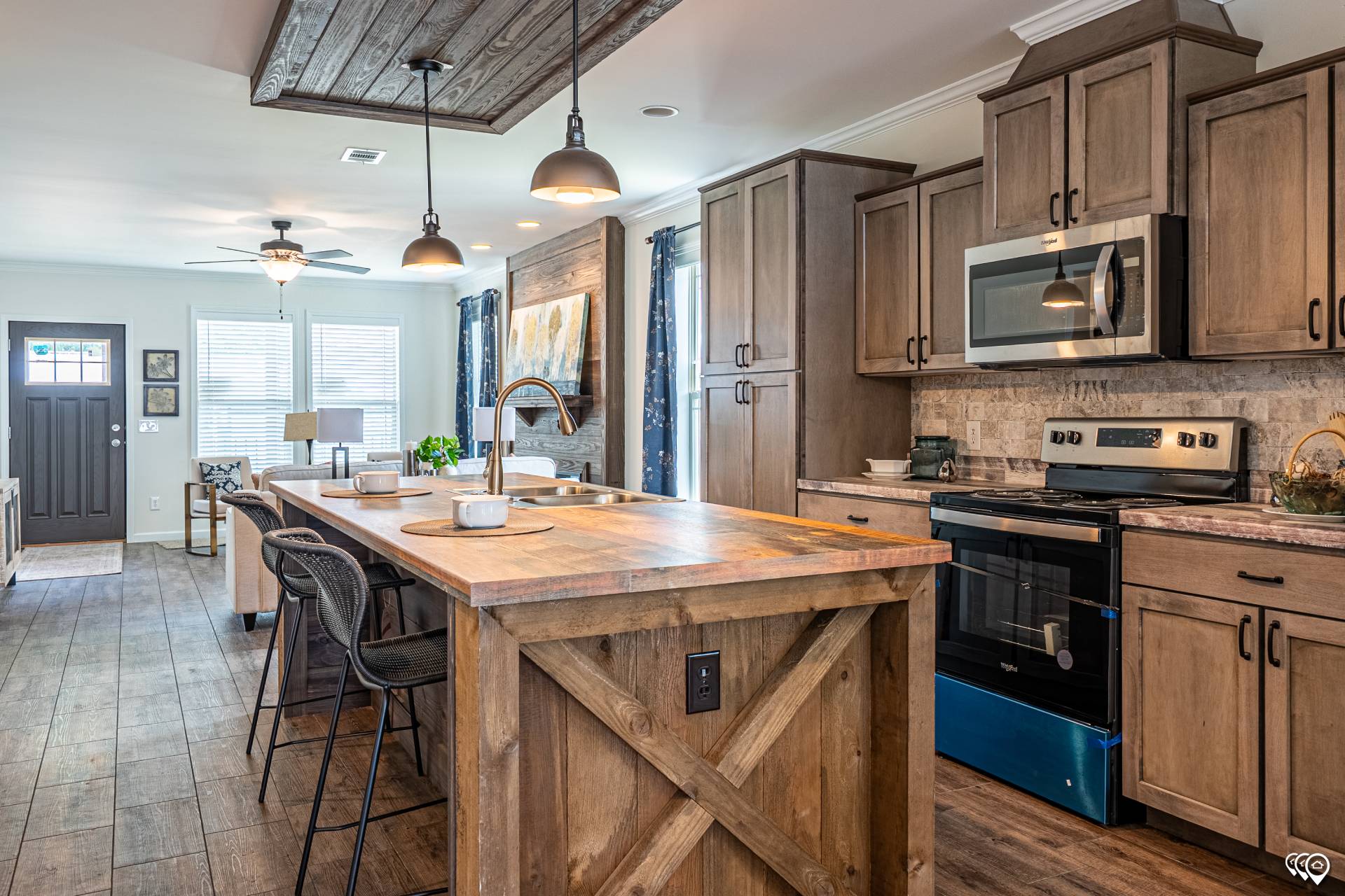 Spacious kitchen with rustic wood cabinets and island, pendant lights, stainless steel appliances, and a cozy dining area in soft, natural lighting.