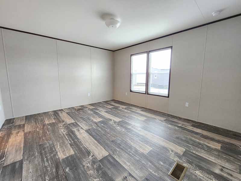 Empty room with light beige walls, dark wood-patterned flooring, and two large windows. It appears bright and spacious, conveying simplicity and potential.