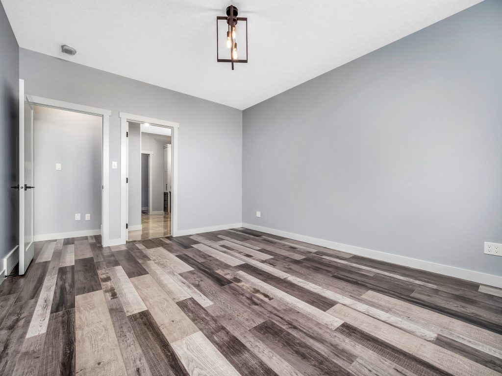Empty room with gray walls and a ceiling light fixture. The floor has wide plank wood in varying shades of gray, creating a modern, clean look.