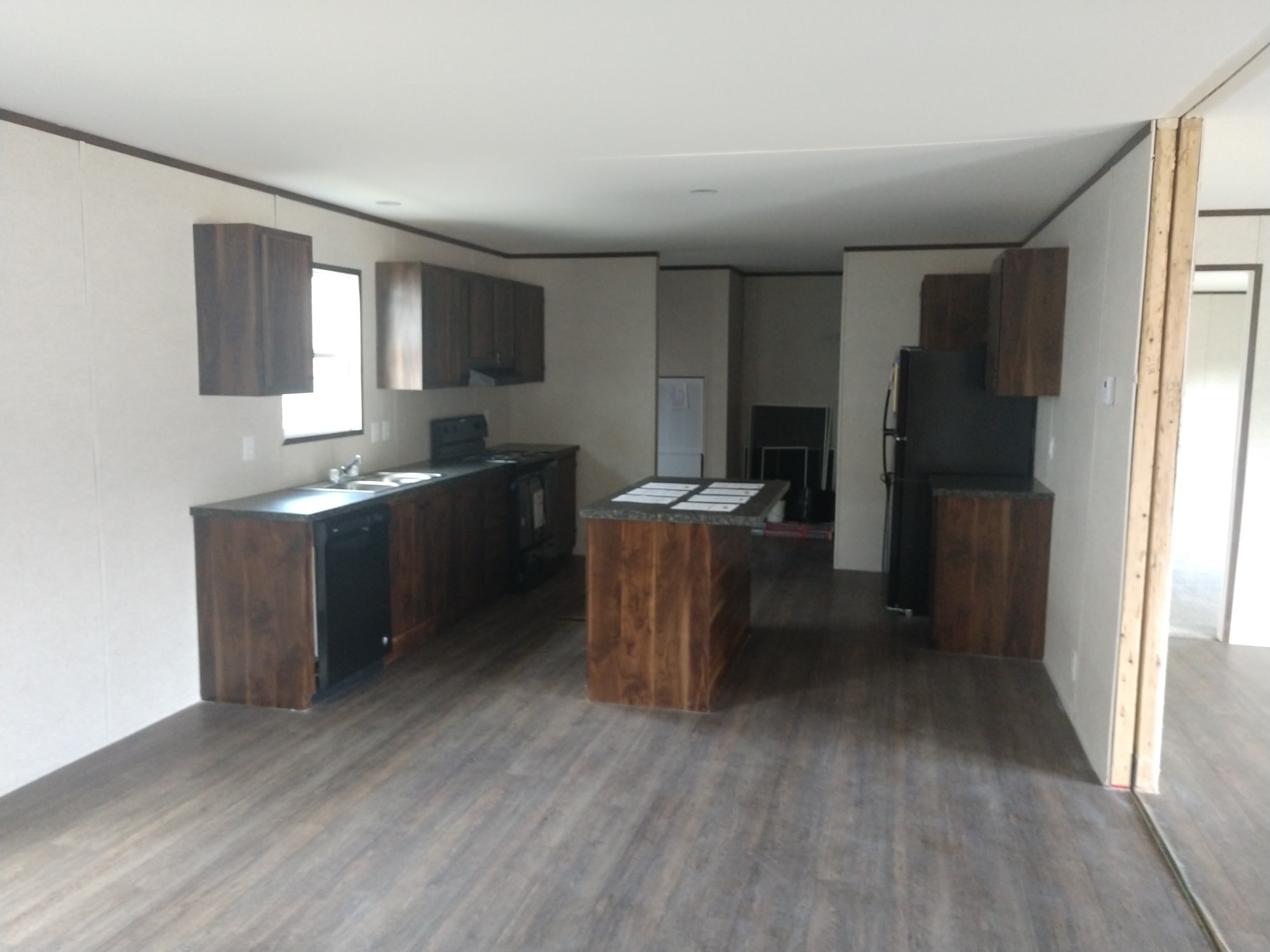 A modern kitchen with dark wood cabinets, a central island, stainless steel appliances, and wood flooring, creating a warm and inviting atmosphere.