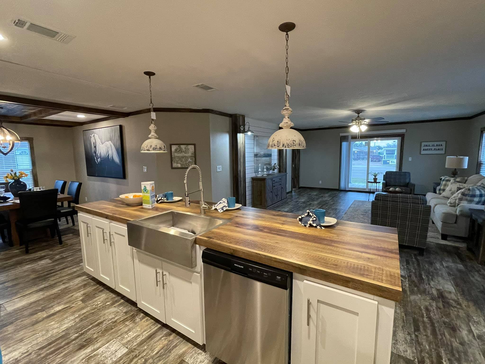 Spacious kitchen with white cabinets and wooden countertops, featuring a stainless steel fridge, blue microwave, and white dishes. Bright, modern ambiance.
