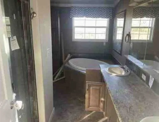 A bathroom with a large window, circular bathtub, and wide countertop with a sink. Reflective surfaces and patterns create a modern, calm atmosphere.