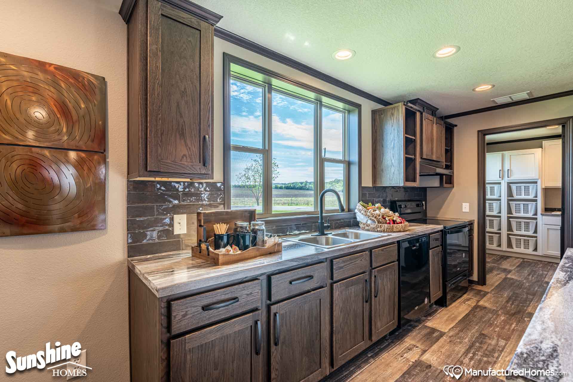 Spacious kitchen with dark wood cabinets, a double sink, and a window showcasing a scenic view. Cozy atmosphere with warm lighting and modern decor.