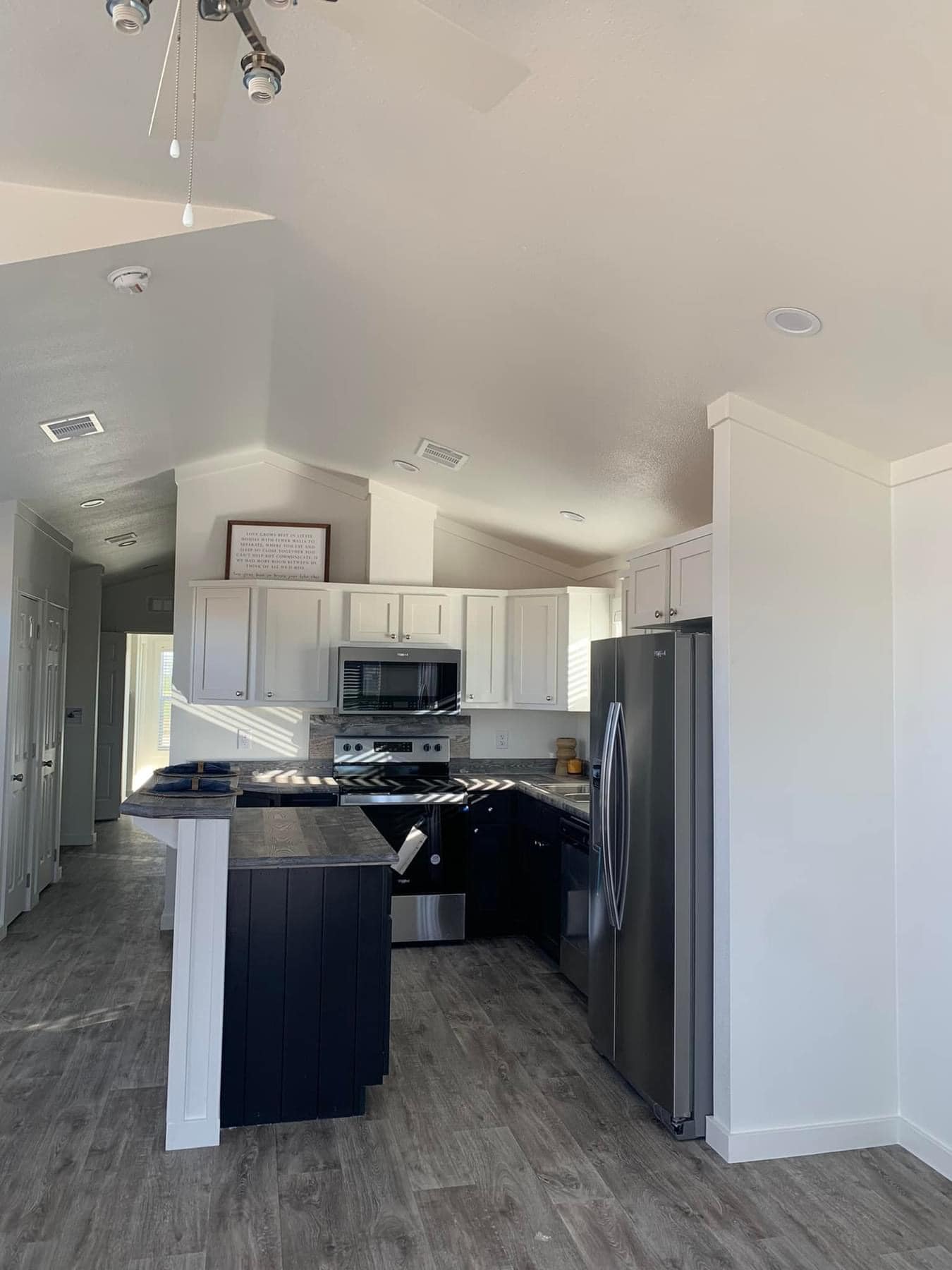 Bright modern kitchen with white cabinets, stainless steel appliances, and dark countertops. Light wood flooring and natural light create an inviting ambiance.