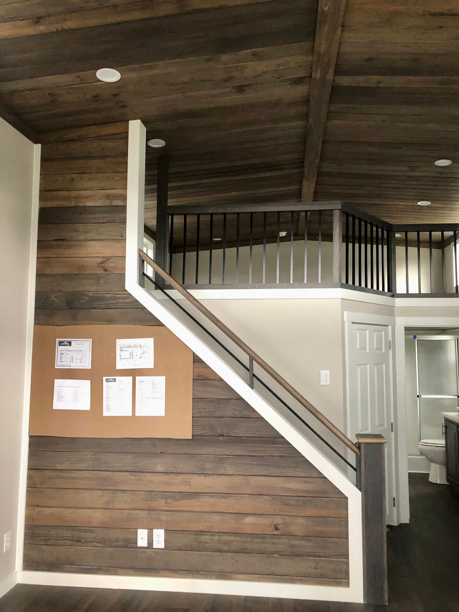 Triangular window with white trim above a set of double doors. The window sits on a beige, paneled wall, exuding a modern and clean aesthetic.