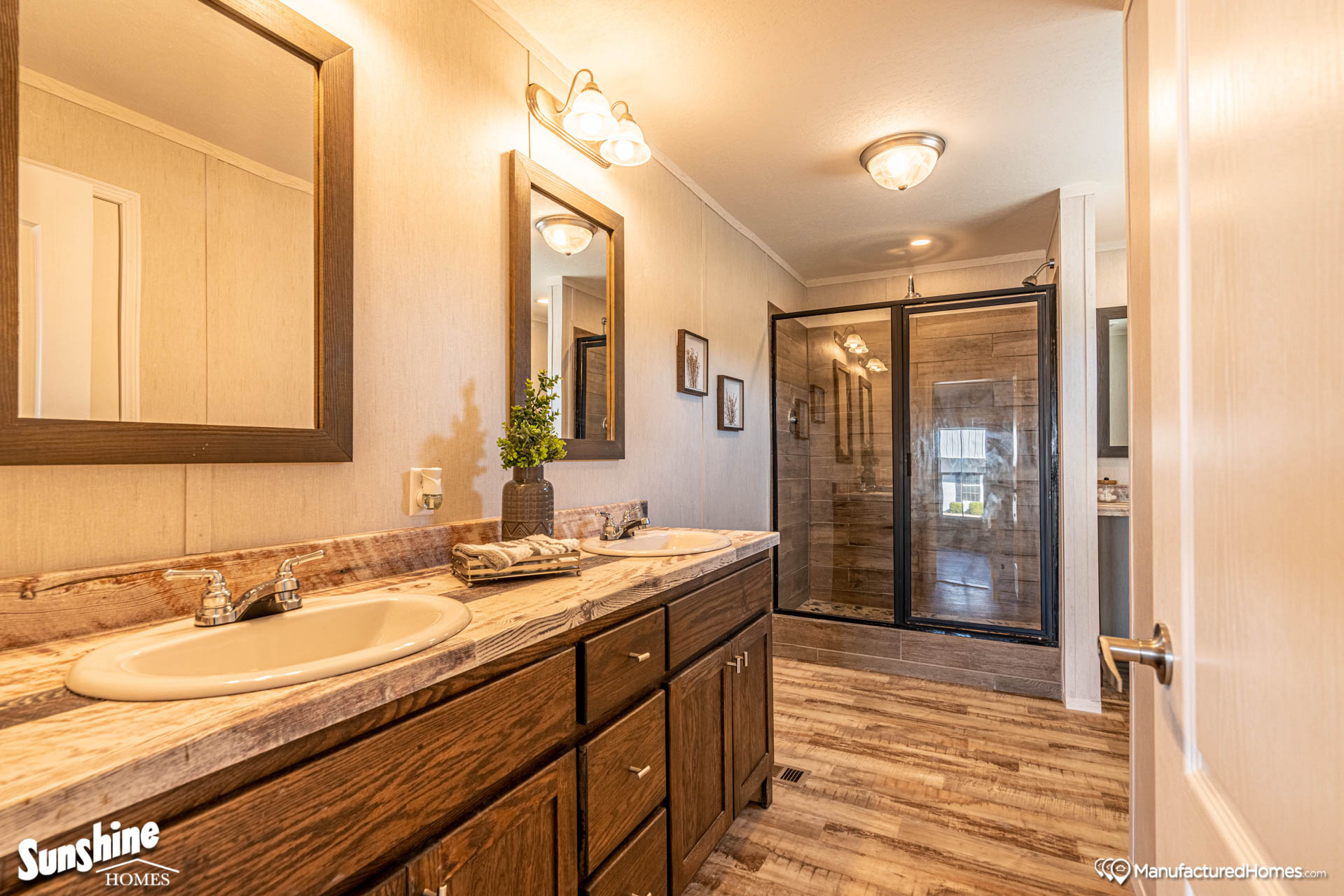 Spacious room with wood flooring, light gray walls, and a ceiling light. Open doors reveal a closet with shelving and a bathroom with a modern design.