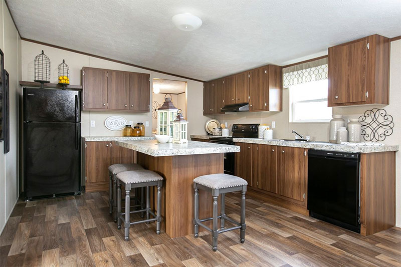 A cozy kitchen with brown wood cabinets, island with stools, and modern appliances. The room has natural light, decorative jars, and a warm, inviting feel.