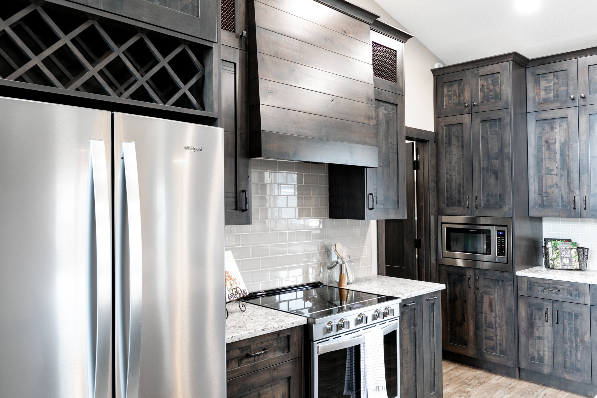 Modern kitchen with dark wood cabinets, a stainless steel fridge, and stove. Neutral backsplash and countertops add a sleek, clean look.