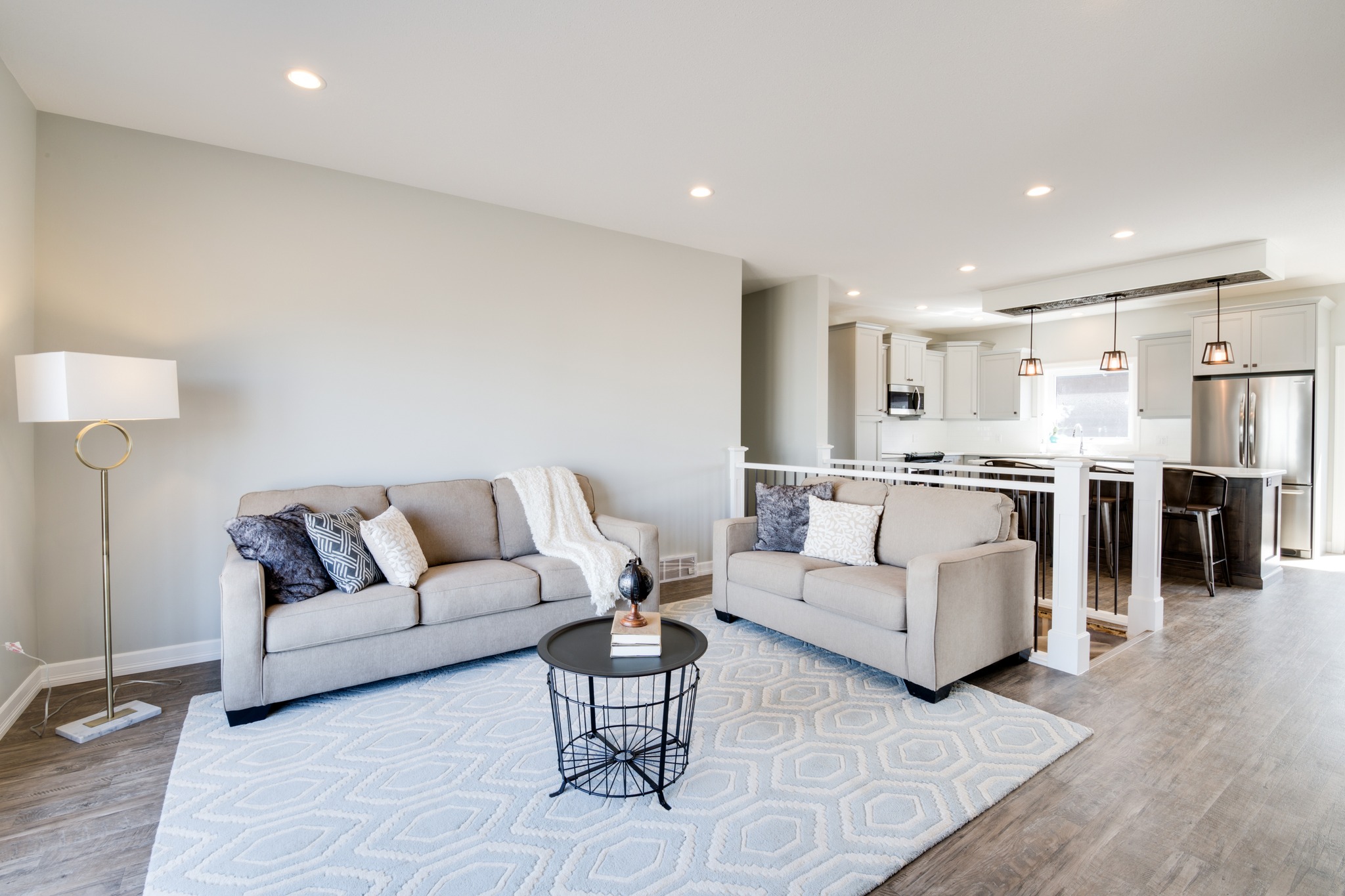 Modern kitchen with rustic charm, featuring a large wooden island, pendant lights, barn door, dining table, and a cozy living area, exuding warmth.