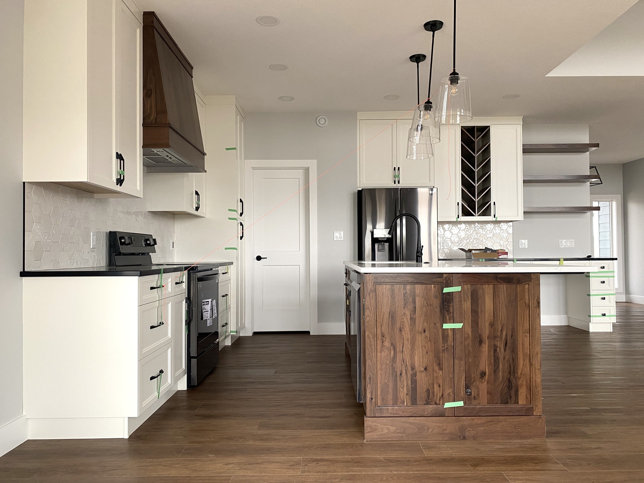 Modern kitchen with white cabinets, wood island, and stainless steel appliances. Pendant lights hang above, creating a warm, inviting atmosphere.