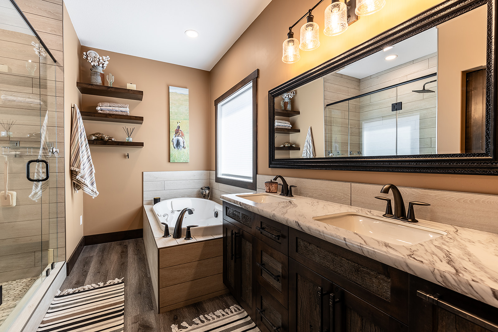 Modern bathroom with warm tones, featuring a double sink vanity, marble countertop, soaking tub, glass-enclosed shower, and shelves with decor. Cozy ambiance.