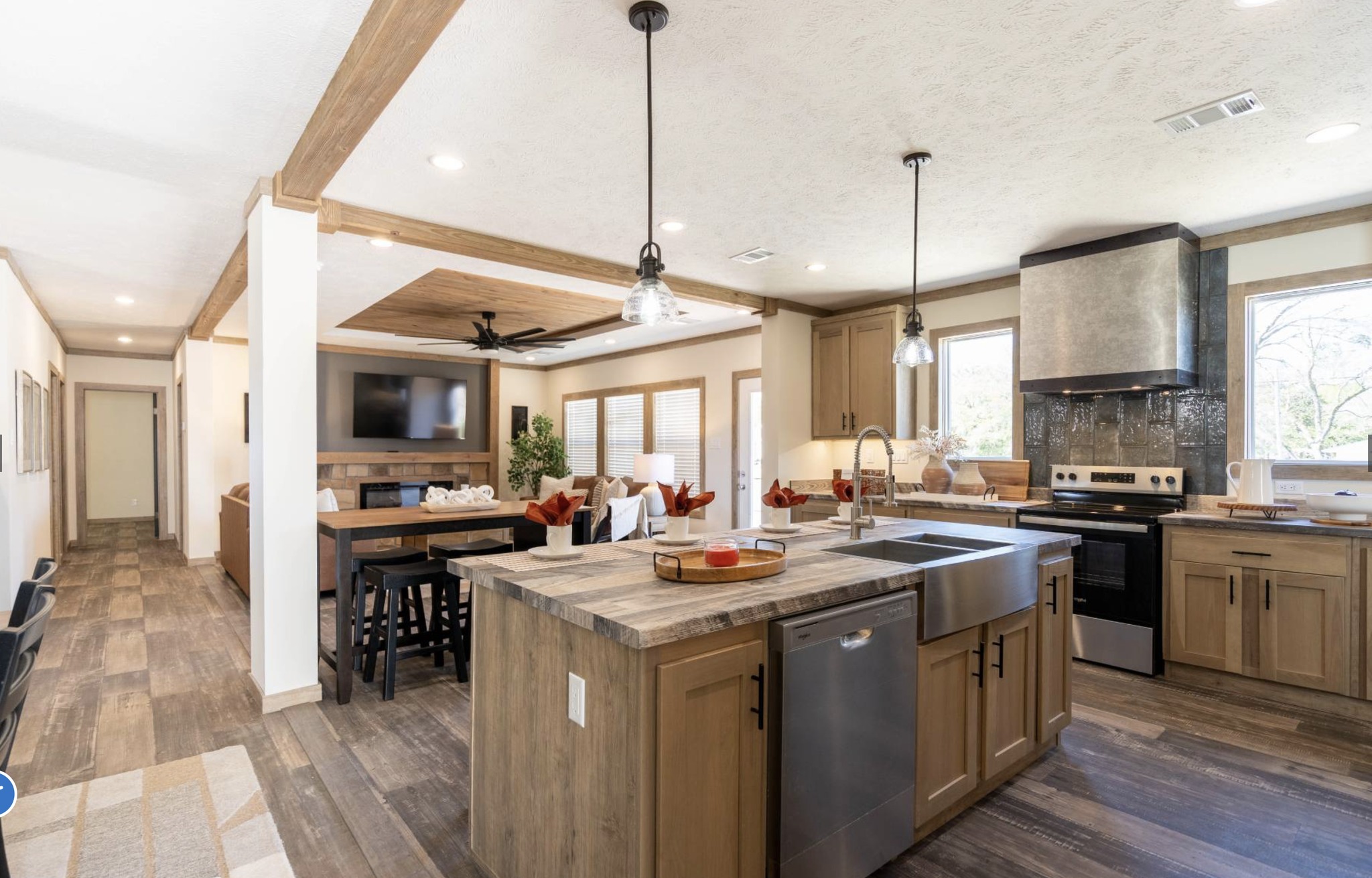 Spacious modern kitchen and dining area featuring wooden cabinetry, stainless steel appliances, and pendant lighting. The open layout conveys warmth.