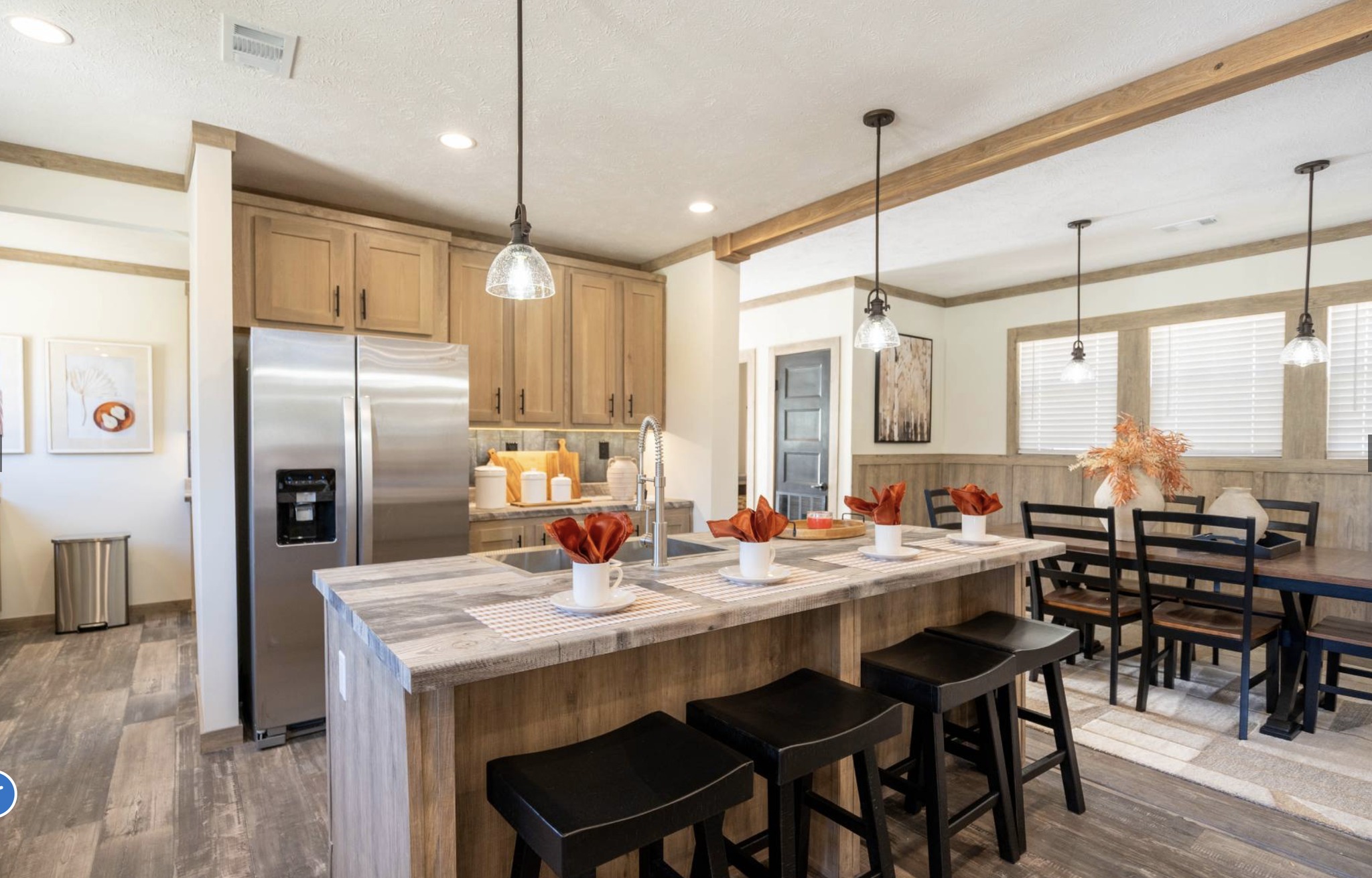 Warm, inviting living room with two brown leather sofas, a wooden coffee table, and a TV above a stone fireplace. Soft lighting and neutral tones.