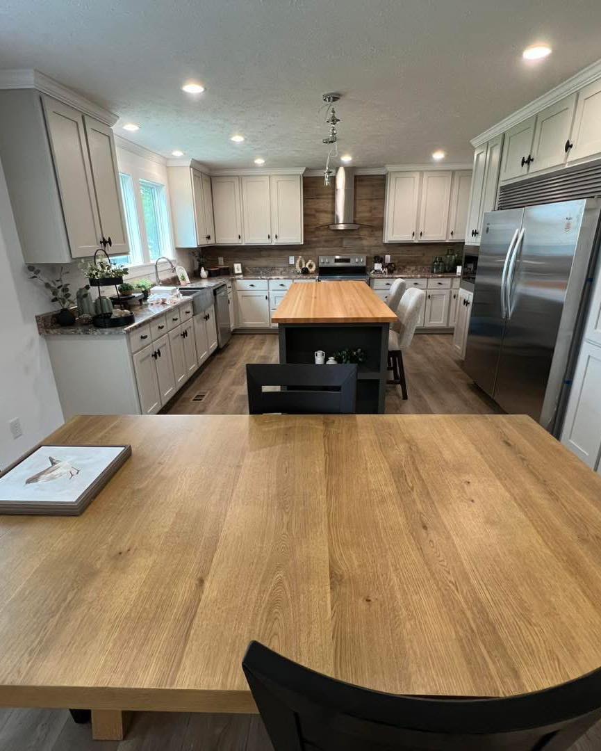 Spacious kitchen with wooden tables, white cabinets, stainless steel appliances, and a central island. Bright, inviting, and modern atmosphere.