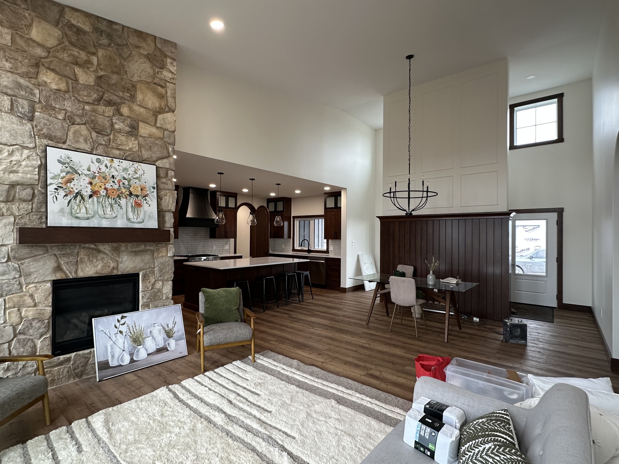 Spacious living area with a modern kitchen, stone fireplace, and dining area. Warm, earthy tones and contemporary decor create an inviting ambiance.
