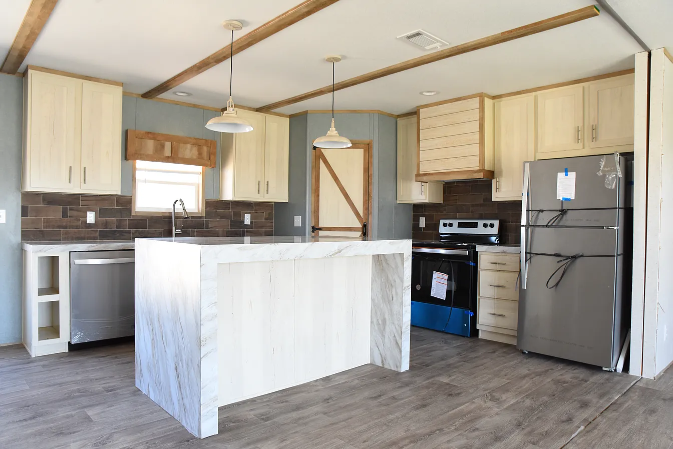 Modern kitchen with light wood cabinets, marble island, and pendant lights over a wooden floor. Stainless steel appliances and a rustic barn door add charm.