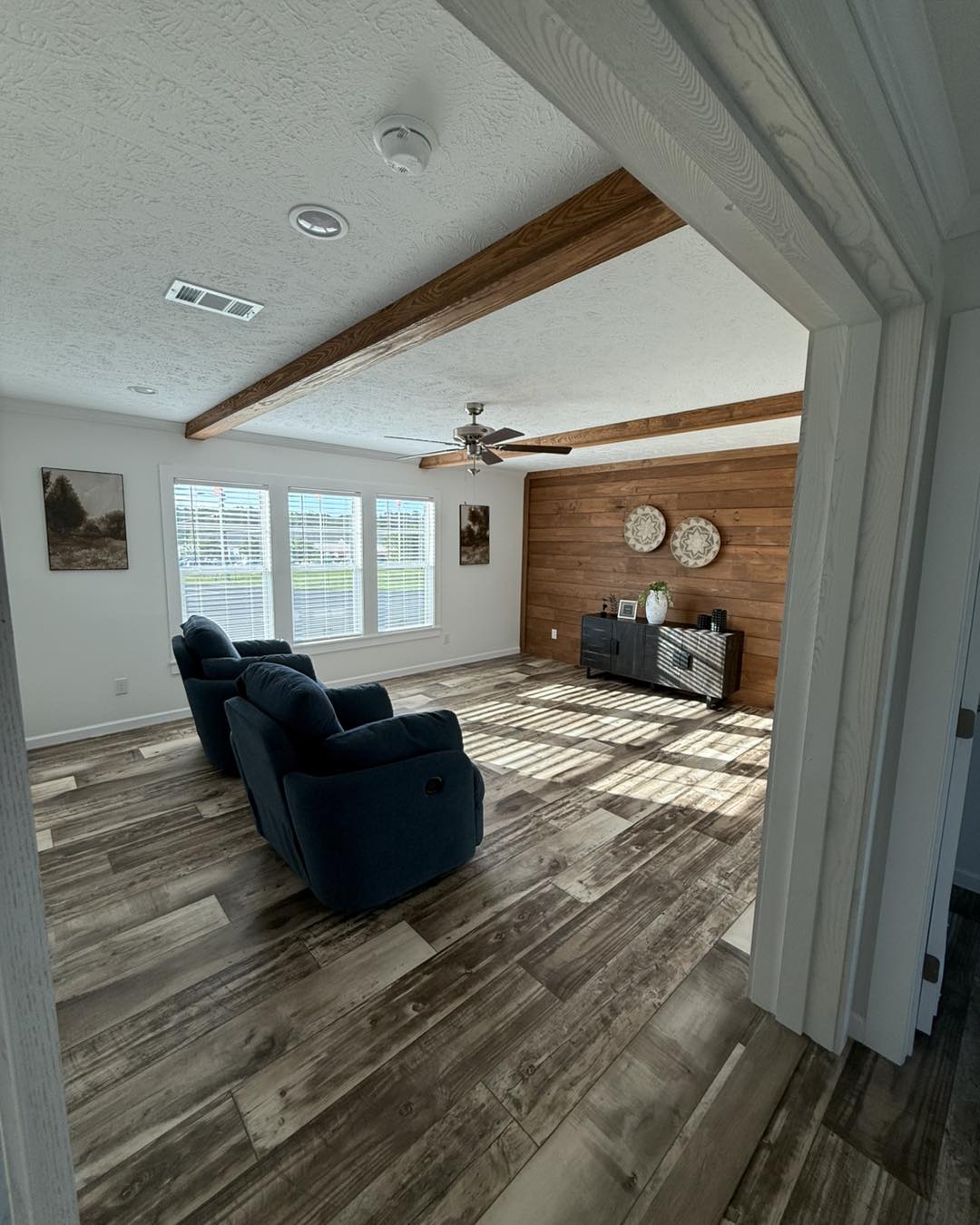 Narrow, well-lit utility room with white cabinets, dark countertops, and a sink. Wooden floor and door with window panels. Clean and organized.