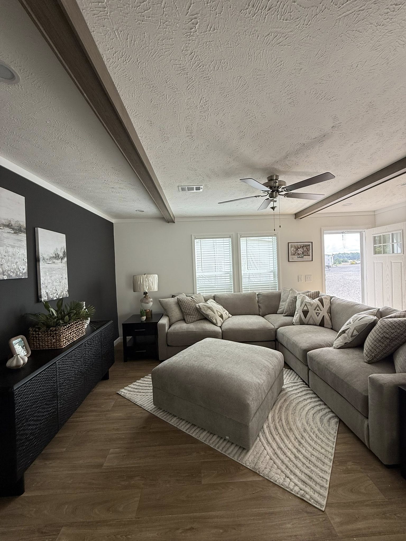 Modern kitchen with a long marble island, bar stools, and sleek appliances. White cabinets and wood flooring offer a clean, contemporary feel.