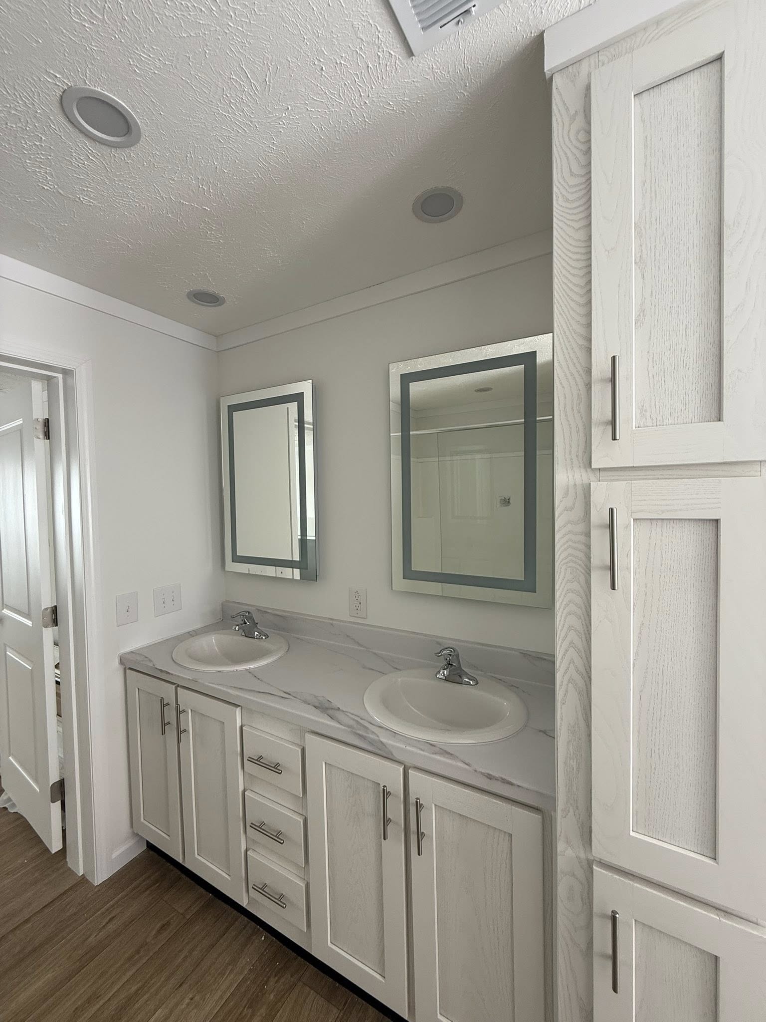 Narrow beige closet with wooden floor and an empty dark wooden rod along the wall. Boxes with household items are stacked at the far end. Minimalist and organized.