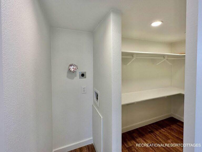 Small walk-in closet with white walls and wooden floor. Features a shelf and hanging rod under a recessed light, creating a clean, minimal look.