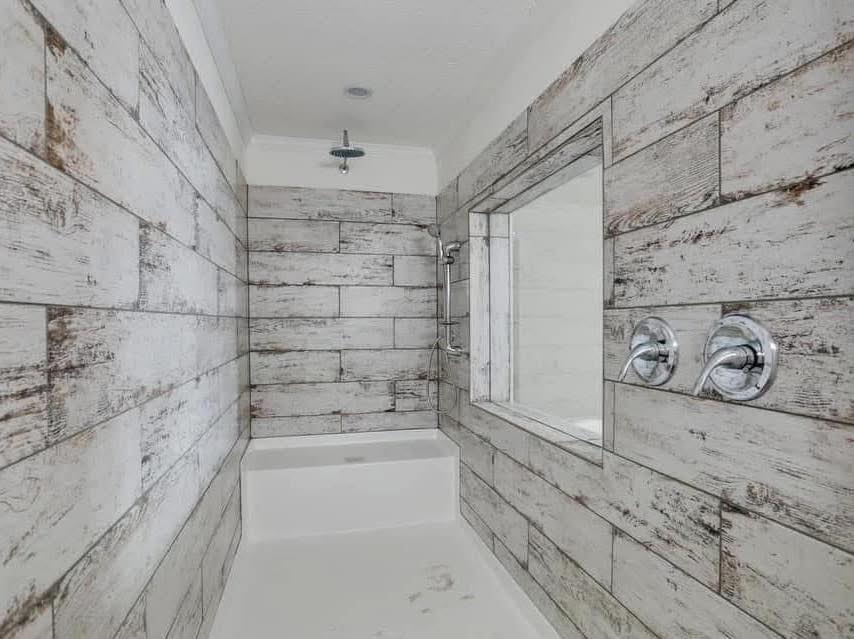 Shower with rustic wood-look tile walls, featuring a built-in bench and a modern rainfall showerhead. The atmosphere is warm and inviting.