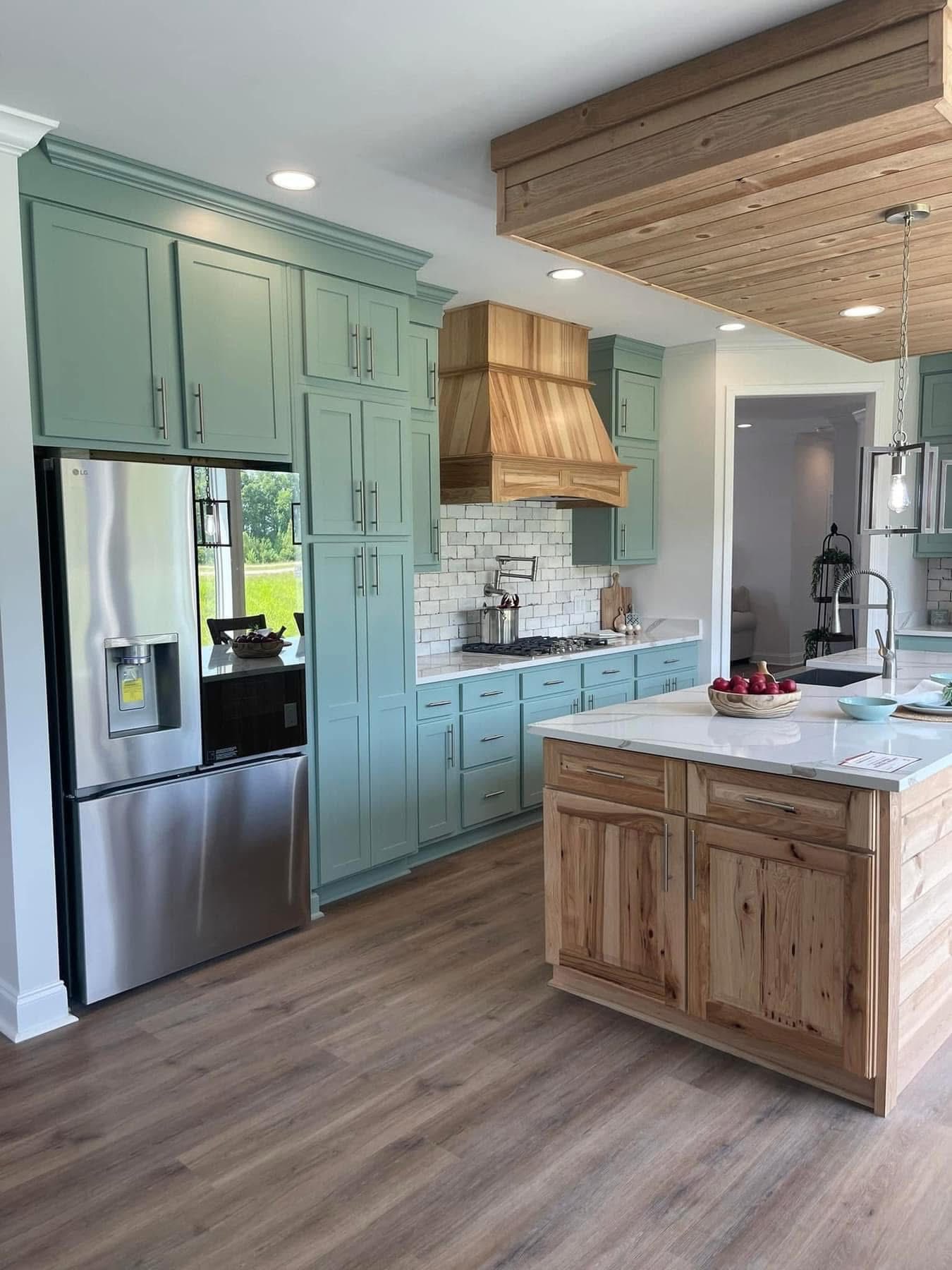 Stylish kitchen with light wood floors, mint green cabinets, stainless steel appliances, and a wooden island. Bright, airy, and modern feel.