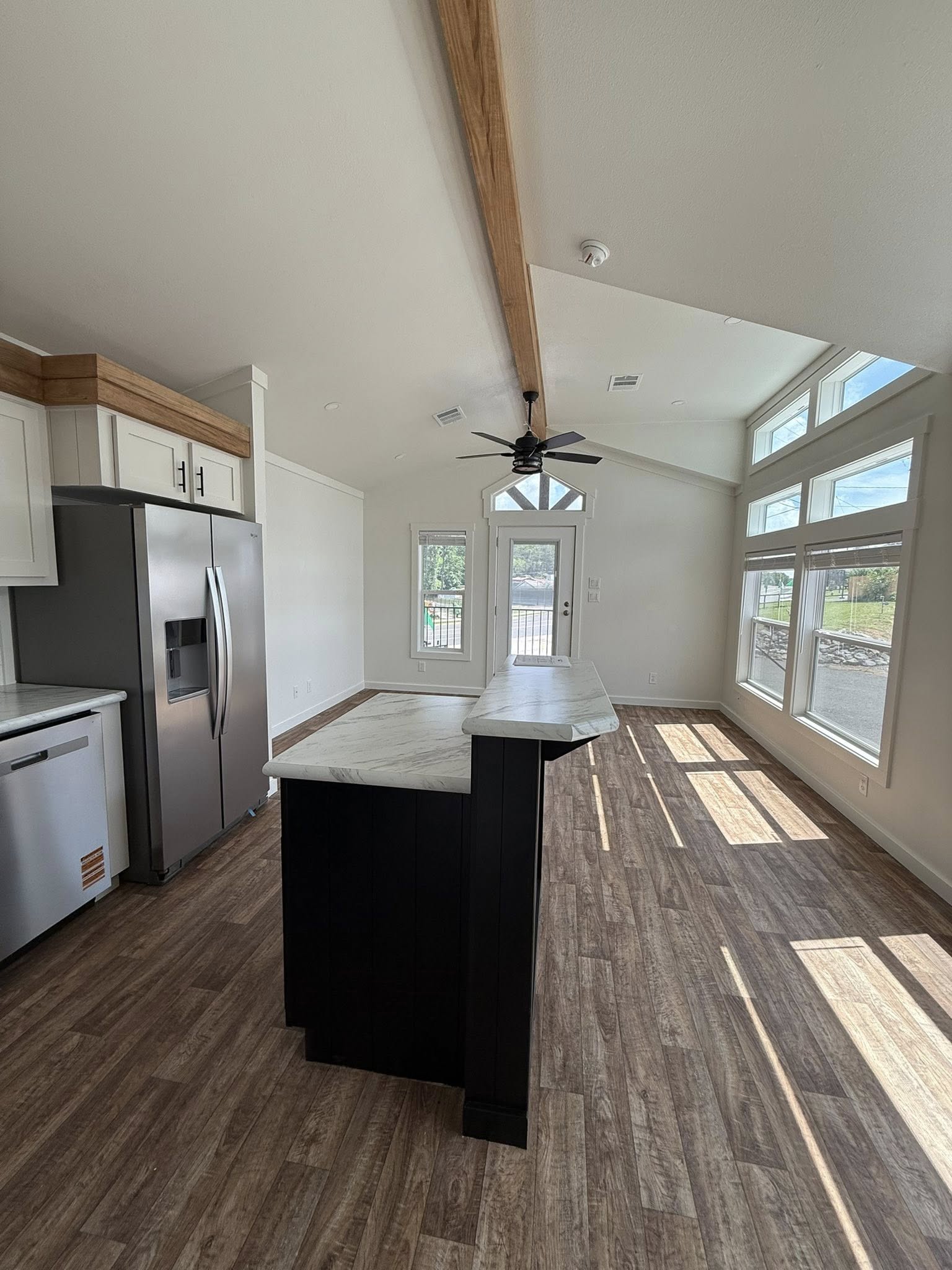 Modern kitchen with a vaulted ceiling and wood beam. Features a large island with marble top, stainless steel appliances, and ample natural light.