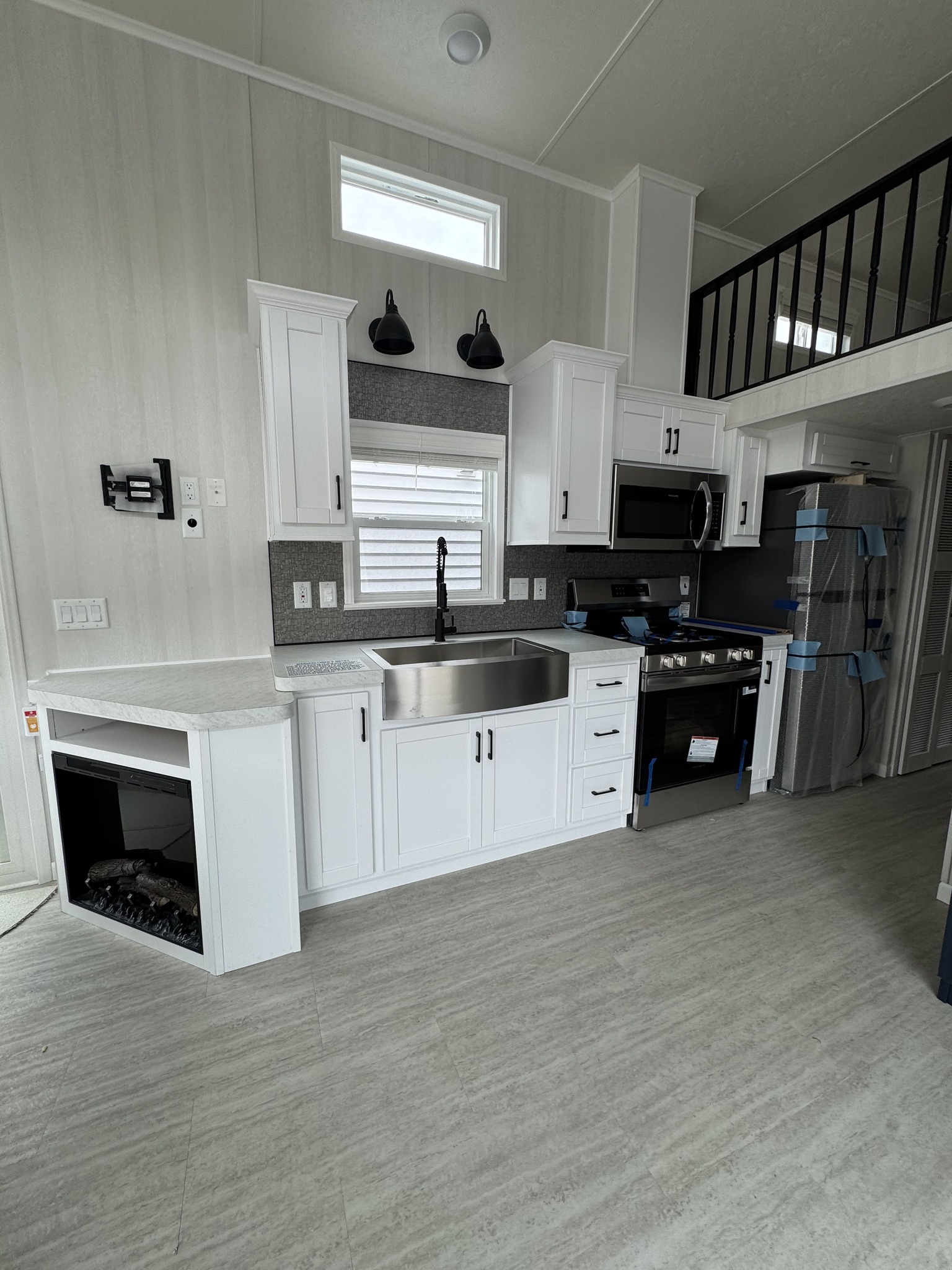 Modern kitchen with sleek white cabinets, large stainless steel sink, and high-end appliances. The space feels bright and inviting.