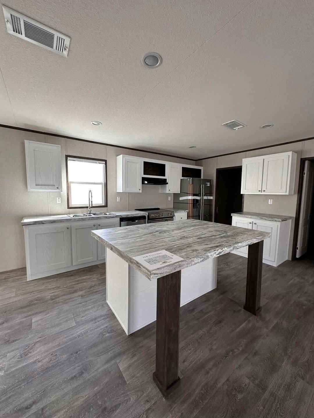 Modern kitchen with gray wood floors, white cabinets, and marble island. Stainless steel appliances and soft lighting create a sleek, minimalist ambiance.