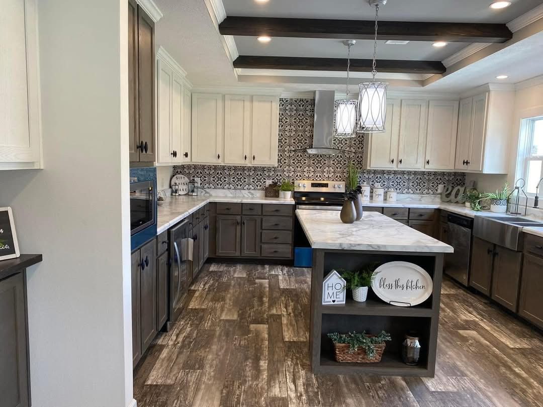 Spacious kitchen with a warm, inviting feel, featuring two-tone cabinets, patterned backsplash, marble countertops, and decorative pendant lights.