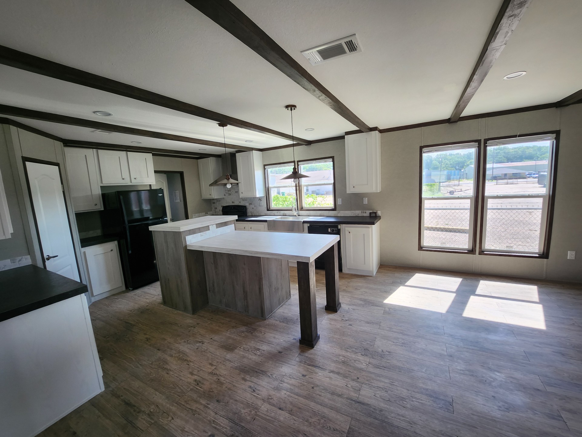 Modern kitchen with wood floors, white cabinetry, and a central island. Large windows allow abundant natural light. Neutral tones create a cozy atmosphere.