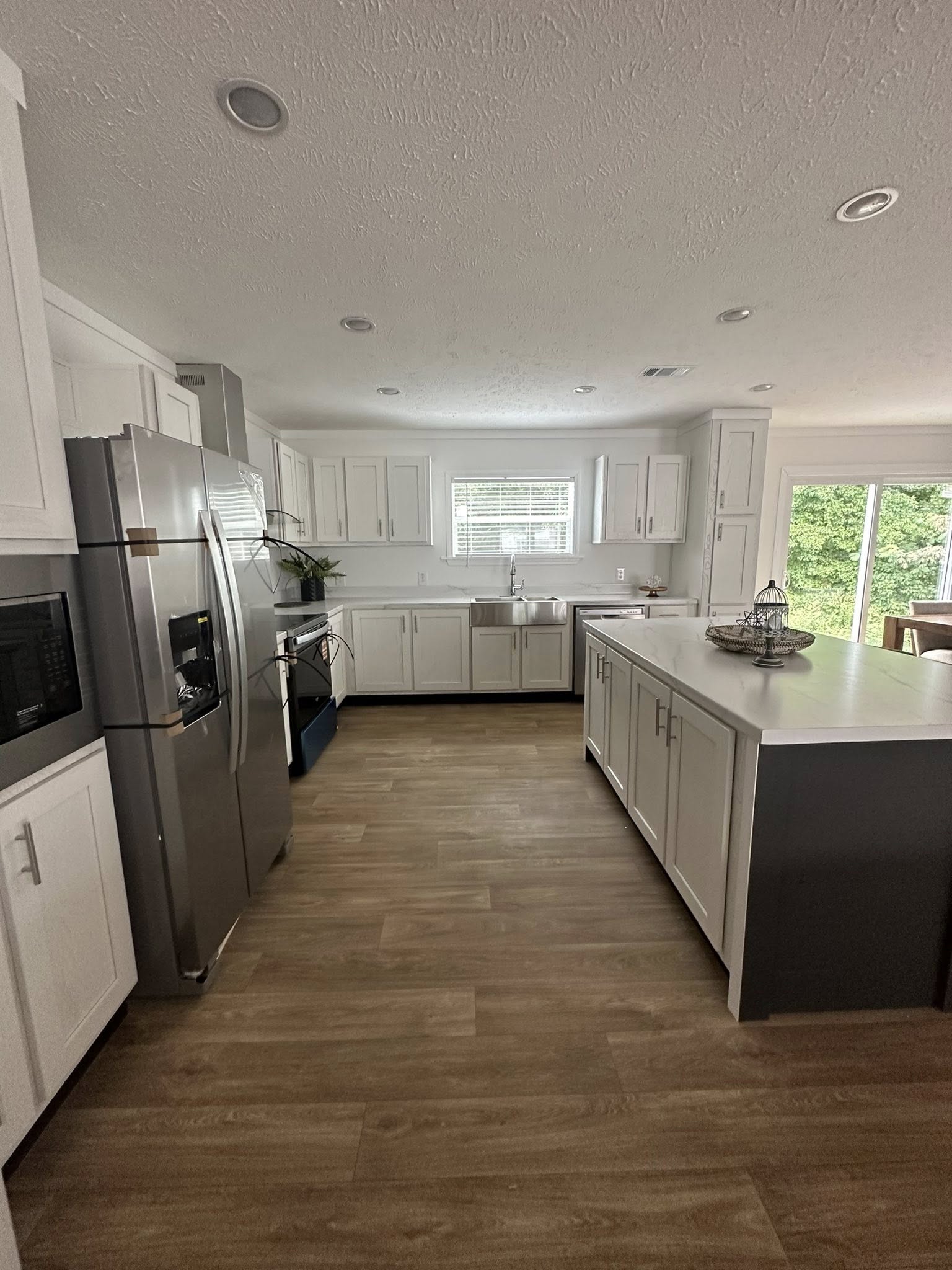 Spacious modern kitchen with white cabinets, stainless steel appliances, and a large island. Sunlight streams through windows, creating a cozy ambiance.