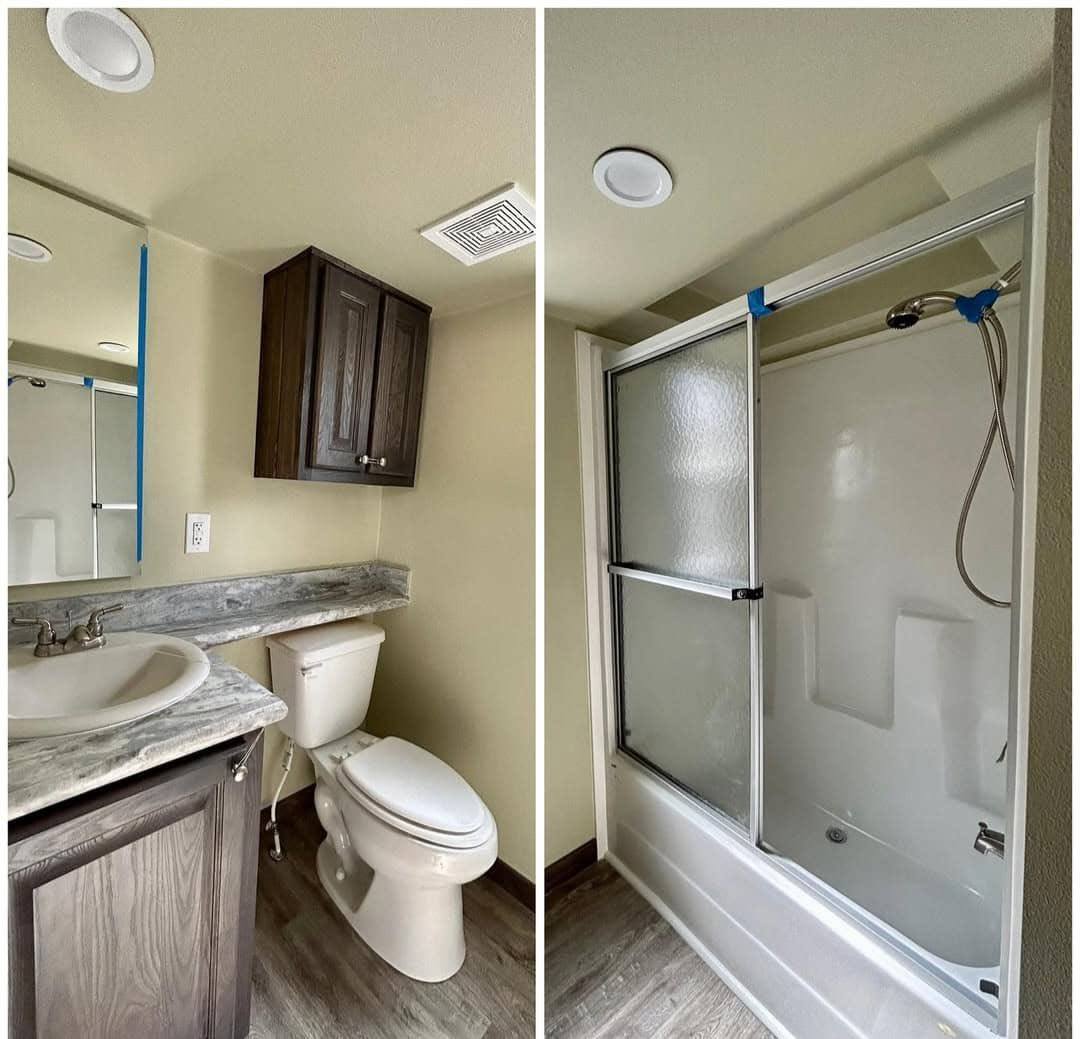 A modern bathroom features a sink and toilet with a marble countertop and dark wood cabinet. Adjacent is a shower with frosted glass doors. The ambiance is clean and minimalist.