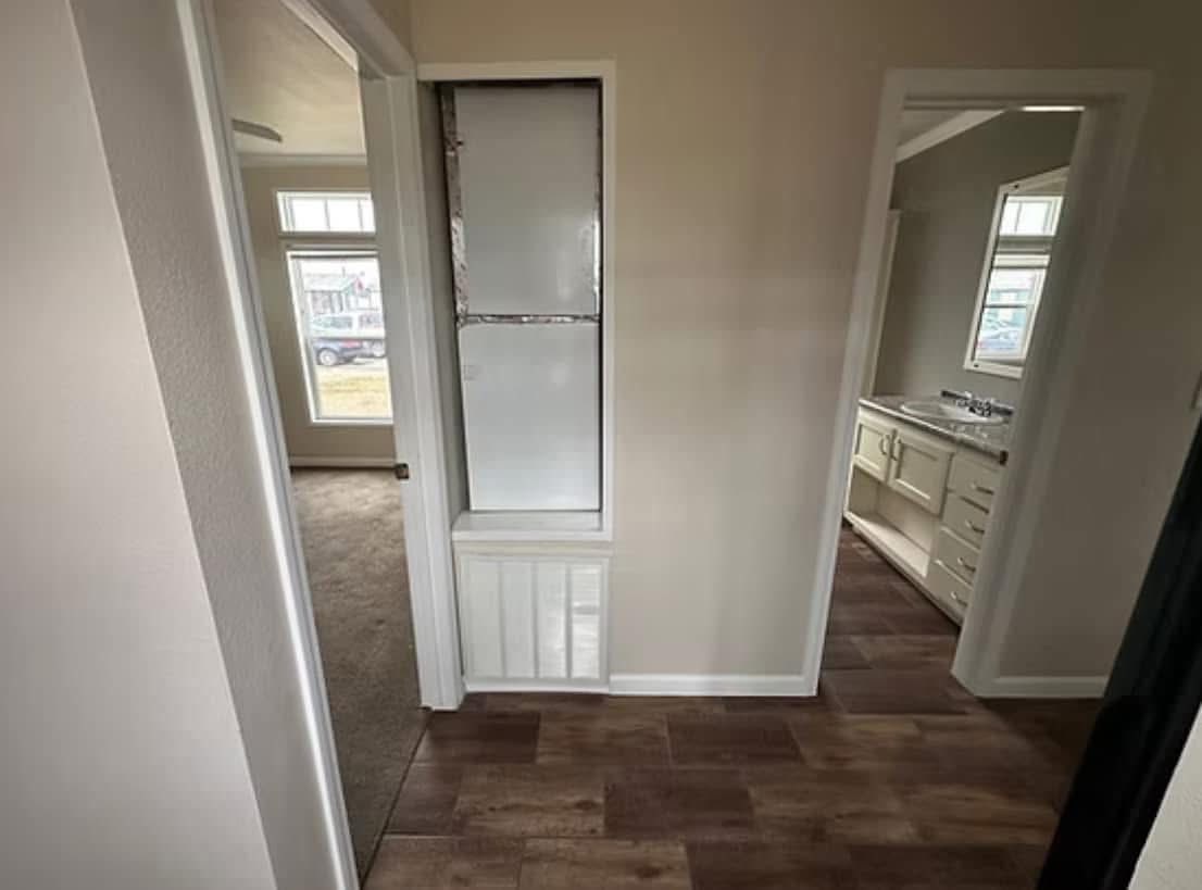 Cream-colored kitchen cabinets with black countertops, featuring open shelving and a mosaic tile backsplash. A hint of modern, cozy design.