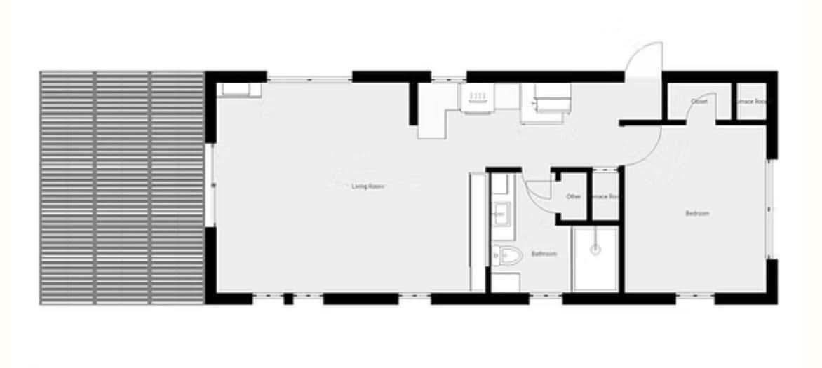 Floor plan of a rectangular building showing a large living room, bedroom, bathroom, entrance room, kitchen, and a patio on the left side.