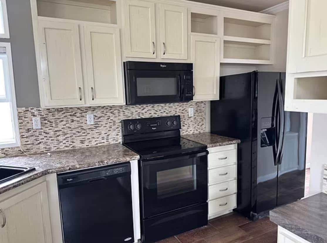 Spacious kitchen with cream cabinets, black appliances, and a tiled backsplash. The sleek design feels modern, organized, and inviting.